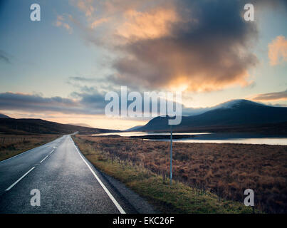 Vista del loch rurale strada al tramonto, Assynt, North West Highlands, Scotland, Regno Unito Foto Stock