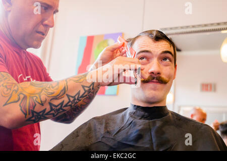 Giovane uomo con i baffi manubrio avente il suo taglio di capelli Foto Stock