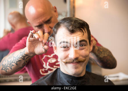 Giovane uomo avente il suo taglio di capelli Foto Stock