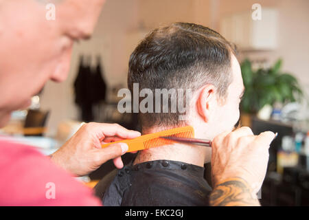 Giovane uomo avente il suo taglio di capelli Foto Stock