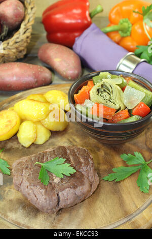 Struzzo arrosto bistecca con patate al forno su una tavola di legno Foto Stock