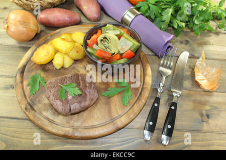 Struzzo arrosto bistecca con patate al forno su una tavola di legno Foto Stock