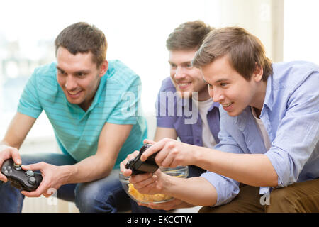 Sorridendo gli amici per giocare con i videogiochi a casa Foto Stock