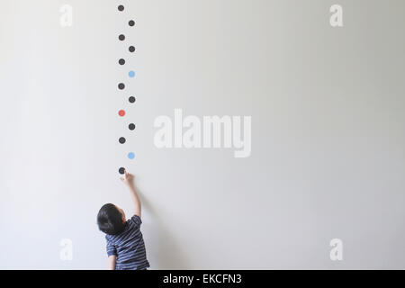 Ragazzo che cerca di scegliere un punto da un muro Foto Stock