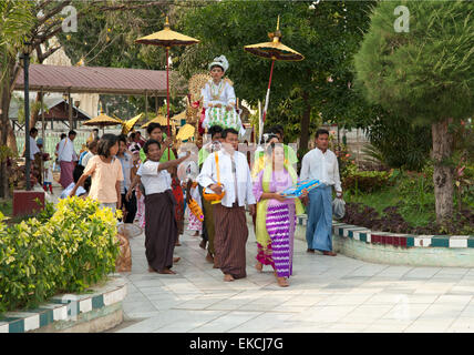 I bambini e le loro famiglie parade di vistosi bejeweled costumi in loro venuta di età cerimonia in Myanmar Mandalay Foto Stock