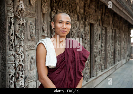 Questo Monaco si trova di fronte il teak intagliato parete del Shwenandaw Kyaung Pagoda in Mandalay MYANMAR Birmania Foto Stock