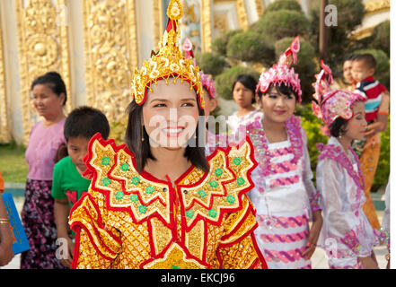 Una giovane ragazza birmano in vistosi bejeweled costumi nei prossimi di età cerimonia in Myanmar Mandalay Foto Stock