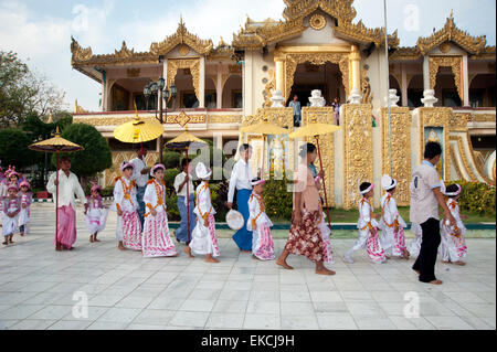 I bambini e le loro famiglie parade di vistosi bejeweled costumi in loro venuta di età cerimonia in Myanmar Mandalay Foto Stock