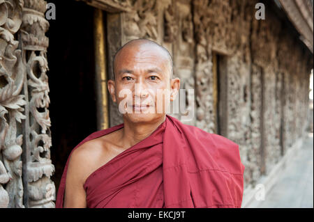 Questo Monaco si trova di fronte il teak intagliato parete del Shwenandaw Kyaung Pagoda in Mandalay MYANMAR Birmania Foto Stock