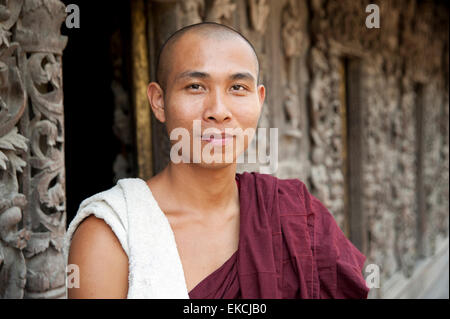 Questo Monaco si trova di fronte il teak intagliato parete del Shwenandaw Kyaung Pagoda in Mandalay MYANMAR Birmania Foto Stock