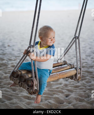 Baby sitting su una oscillazione di bambù Foto Stock