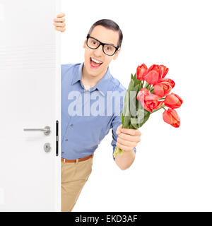 Giovane uomo con gli occhiali di entrare in una stanza con un bouquet di tulipani rossi nel suo canto isolato su sfondo bianco Foto Stock