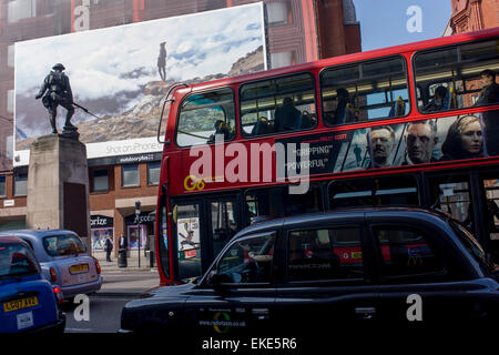 Un gigante di annuncio tramite Affissioni per l'uso di iphone visto sul lato di una centrale di Londra edificio, giustapposti con bus e pubblicità a WW1 memorial Soldier of the Royal Fusiliers. Foto Stock