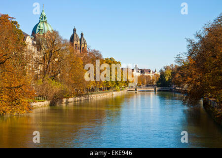 Monaco di Baviera, fiume Isar in autunno con foglie rosse e la vista di san Luca le cupole della chiesa Foto Stock