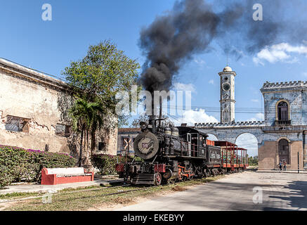 Treno a vapore con denso fumo nero si arresta in corrispondenza di un magnifico arco sul percorso di Cardenas in Cuba Foto Stock