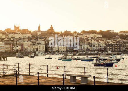 St Peter Port, capitale dell'isola di Guernsey. Caldo tramonto, guardando ad ovest del porto con barche da pesca e case della città. Foto Stock