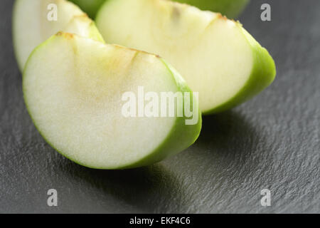 Verde mela acerba sulla scheda di ardesia a fette Foto Stock