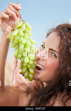 Donna perfetta mangiare uva nel campo di grano. Il Picnic. Foto Stock