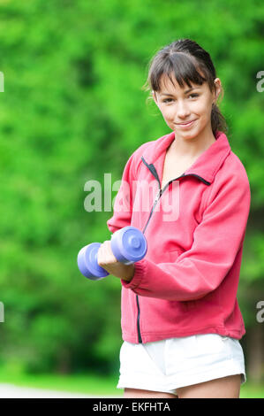 Ragazza facendo esercizio dumbbell outdoor Foto Stock