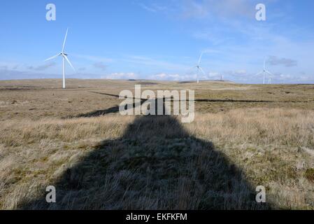 Una lunga ombra di una turbina che si estende attraverso il moro a Whitelee wind farm in Scozia, Regno Unito Foto Stock