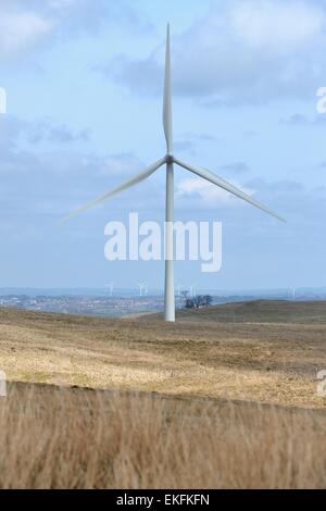 Si suppone che il vento eserciti una turbina azionata ad una fattoria eolica in Scozia, nel Regno Unito con la città di Glasgow dietro di esso. Foto Stock