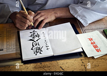 Giappone, isola di Honshu, Kanto, Tokyo, monaco facendo una calligrafia. Foto Stock