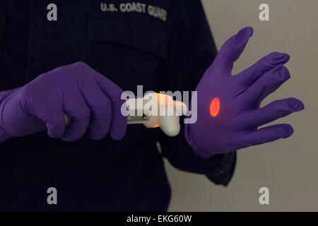 101114: New York - USA Delle dogane e della protezione delle frontiere degli ufficiali condotte una schermatura potenziata al JFK International Airport. Visto qui è una guardia costiera medico persona dimostrando il misuratore di temperatura utilizzata per la presa del passeggero temperature. Donna Burton Foto Stock