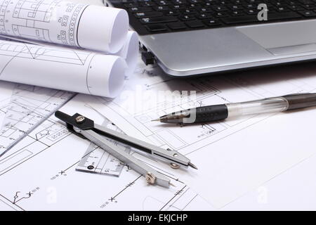 Rotoli di schemi elettrici, disegni di costruzione della casa, accessori per disegno e laptop, disegni Foto Stock
