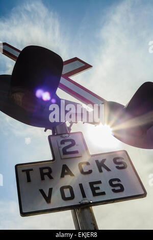 Due treno via segno e la luce con la luce del sole in background Foto Stock