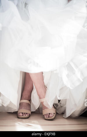 Gambe incrociate di una sposa che indossa il suo matrimonio scarpe Foto Stock