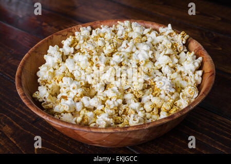 Popcorn speziato in una ciotola di legno su un tavolo nella stanza vivente Foto Stock