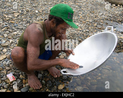 Jungle, Indonesia - 13 Gennaio 2015: un uomo della tribù Korowaya lavaggio oro utilizzando una ciotola Foto Stock