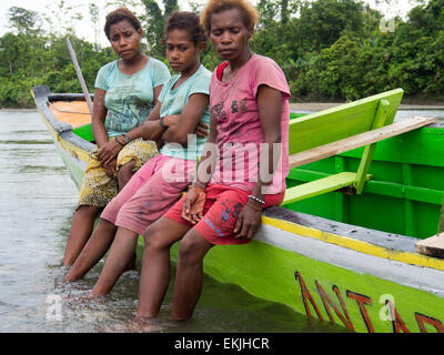 Jungle, Indonesia - 13 Gennaio 2015: le donne della tribù Korowaya seduti sul lato della barca Foto Stock