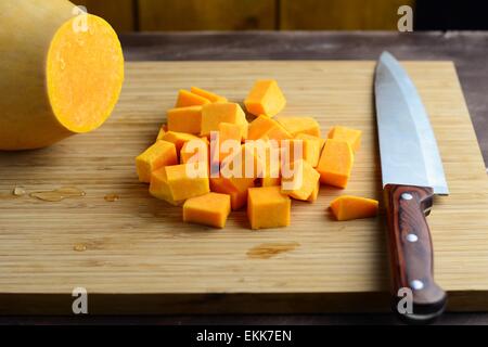 Tagliate a cubetti la zucca sul tagliere di legno. Il processo di cottura Foto Stock