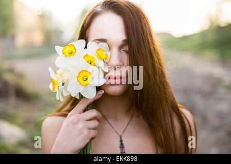 I Capelli rossi ragazza tenendo mazzo di narcisi in primavera