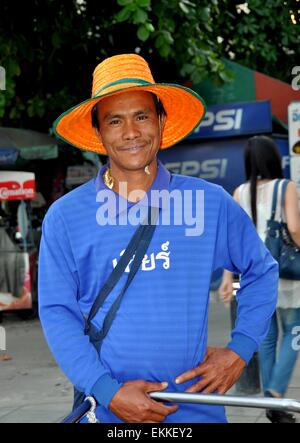 Bangkok, Thailandia: Thai sorridente uomo che indossa un arancio cappello di paglia su Thanon Sathorn Foto Stock