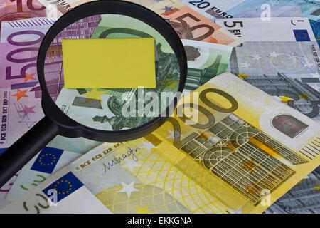 Di Euro (EUR) con una lente di ingrandimento sopra un giallo vuota nota. Foto Stock