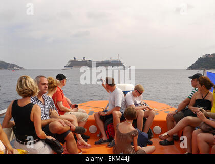 Un gruppo di turisti su una nave di tenera con il celebrity Equinox in background Foto Stock