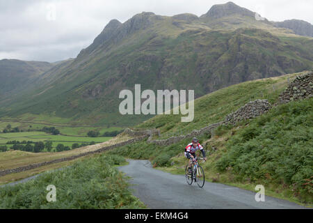 Un uomo in bicicletta nel The Langdale Pikes del Lake District inglese Foto Stock