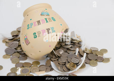 Fracassato denaro cassetta con le monete riversando fuori di esso su sfondo bianco Foto Stock