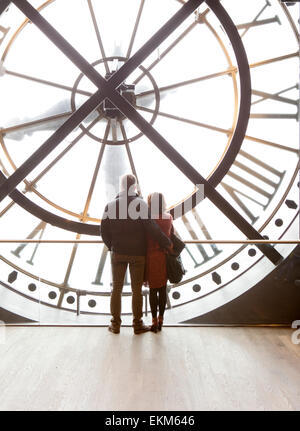 Una coppia romantica peek attraverso il clock di Orsay nel Musée d'Orsay a Parigi Foto Stock