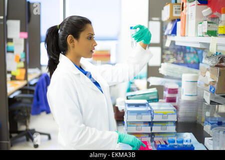 Closeup Ritratto, giovane scienziato in bianco camice fare esperimenti in laboratorio, settore accademico. Foto Stock