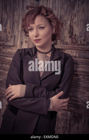 Style redhead girl appoggiata vecchia porta di legno Foto Stock