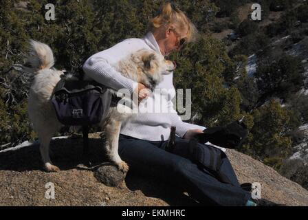 Mia sorella e il suo cane, Goldi, come essi seduto su un masso lungo il sentiero di Sandia Mountains del New Mexico - USA Foto Stock