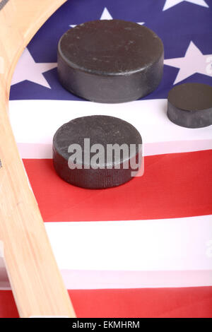 Hockey apparecchiature tra cui un bastone e puck su una bandiera americana per dedurre una patriottica sport americano. Foto Stock