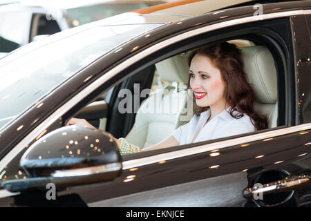 Giovane donna nella nuova auto nello showroom Foto Stock