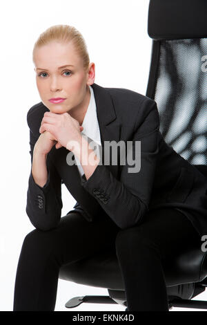 Bionda imprenditrice gravi seduto su una sedia con le mani sotto il mento Foto Stock