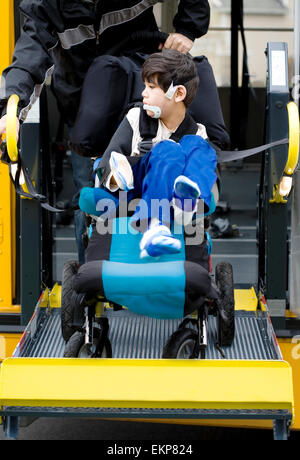 Ragazzo disabili sul bus di scuola di sollevamento per sedia a rotelle Foto Stock