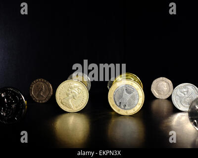Una sterlina britannica e una moneta in euro con altre monete su una superficie nera. Foto Stock