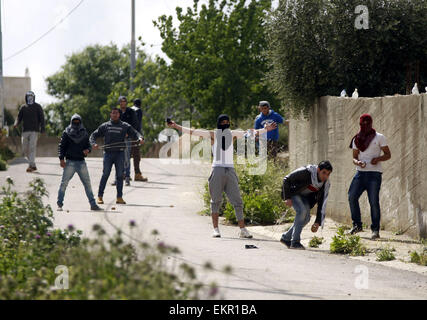 Sinjil, West Bank, Territorio palestinese. Xiii Apr, 2015. Giovani palestinesi scagliare pietre verso forze di sicurezza israeliane durante gli scontri in seguito al funerale di 27-anno-vecchio Mohammed palestinese Jasser Karakra, nel villaggio di Sinjil, nei territori occupati della Cisgiordania città di Ramallah, il 13 aprile 2015. Karakra pugnalato due soldati israeliani in Cisgiordania settentrionale su Aprile 8, 2015, ferendo seriamente uno prima di essere ucciso. Credito: ZUMA Press, Inc./Alamy Live News Foto Stock